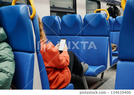 Passenger sitting and scrolling on smartphone with blank screen inside public transport vehicle 134610400