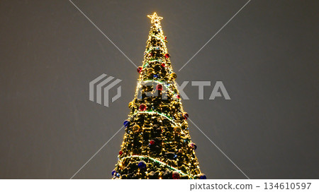 Illuminated Christmas tree with glowing lights against dark night sky Illuminated Christmas tree with glowing lights against dark night sky 134610597