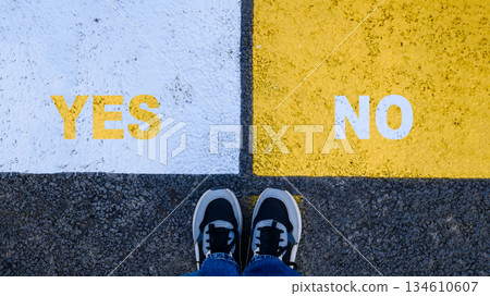 Choice concept with YES and NO markings on pedestrian crossing and feet view Choice concept with YES and NO markings on pedestrian crossing and feet view 134610607