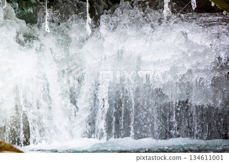 frozen waterfall close up view. icicles hanging above water. cold winter landscape photography on river tyrychka of transcarpathia ukraine. seasonal nature texture. background for climate change frozen waterfall close up view. icicles hanging above water. cold winter landscape photography on river tyrychka of transcarpathia ukraine. seasonal nature texture. background for climate change 134611001