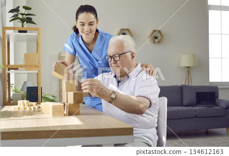 Helpful nurse in retirement home playing games with demented senior male patient Helpful nurse in retirement home playing games with demented senior male patient 134612163