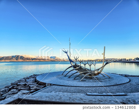 Sun Voyager Sculpture by Waterfront with Mountains and Blue Sky Sun Voyager Sculpture by Waterfront with Mountains and Blue Sky 134612808