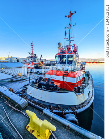 Red Tugboat Moored in Harbor with Calm Water and Blue Sky 134612811