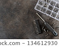 Manual screwdriver, drill bits and assorted screws on dark textured table. DIY home tools. Top view. Copy space. 134612930