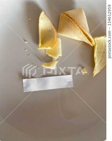 Broken fortune cookies with blank paper strip on plate. Choice aftermath, uncertainty, randomness and symbolic moment of decision Broken fortune cookies with blank paper strip on plate. Choice aftermath, uncertainty, randomness and symbolic moment of decision 134612959