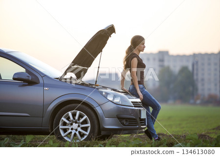 Young woman and a car with popped hood. Transportation, vehicles problems and breakdowns concept. 134613080