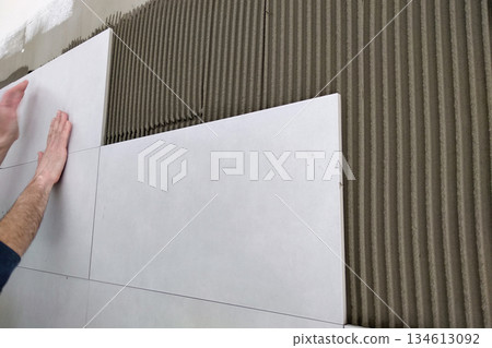 Worker hands putting ceramic tiles on the wall. Worker hands putting ceramic tiles on the wall. 134613092