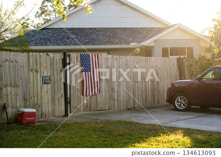 Wooden picket fence on green lawn surrounding property grounds for backyard protection and privacy Wooden picket fence on green lawn surrounding property grounds for backyard protection and privacy 134613093