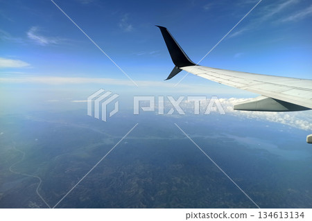 View through airplane window of commercial jet plane wing flying high in the sky. Air travelling concept View through airplane window of commercial jet plane wing flying high in the sky. Air travelling concept 134613134