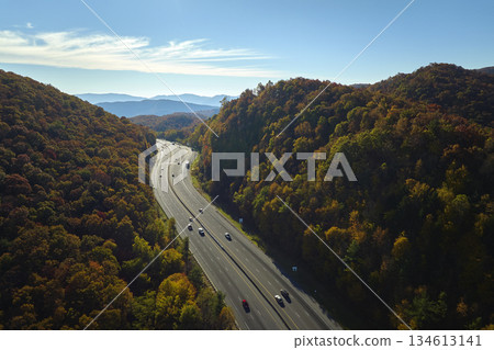 View from above of I-40 freeway route in North Carolina leading to Asheville thru Appalachian mountains with yellow fall woods and fast moving trucks and cars. Interstate transportation concept View from above of I-40 freeway route in North Carolina leading to Asheville thru Appalachian mountains with yellow fall woods and fast moving trucks and cars. Interstate transportation concept 134613141