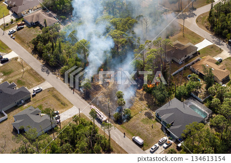 Vegetation fire burns jungle forest near Florida houses as firefighters and fire trucks work to contain flames threatening nearby neighborhoods 134613154