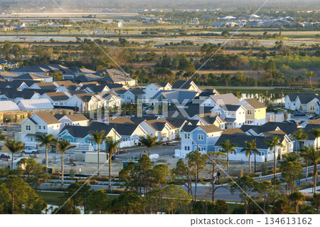 Unfinished frames of inexpensive homes with wooden roof beams under construction. Development of residential housing in US suburbs. Real estate market in the USA 134613162