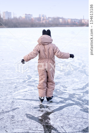 A child in a funny hat learns to skate on the surface of a frozen lake A child in a funny hat learns to skate on the surface of a frozen lake 134613186