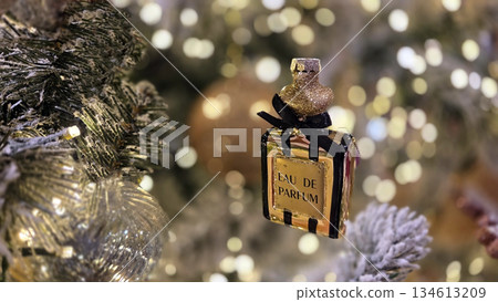 Christmas and new year festive atmosphere with perfume ornament on decorated tree. Horizontal banner. Copy space. For cosmetic shop, perfumery store, beauty salon. Free space for text Christmas and new year festive atmosphere with perfume ornament on decorated tree. Horizontal banner. Copy space. For cosmetic shop, perfumery store, beauty salon. Free space for text 134613209
