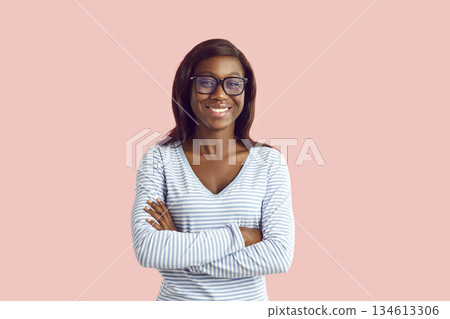 Portrait of happy young African American woman in casual wear and glasses with folded arms 134613306