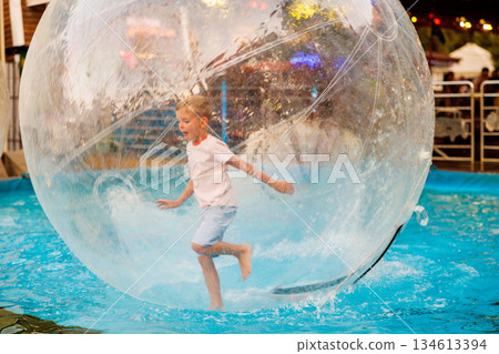Child Enjoying Water Walking Ball Adventure in Pool 134613394