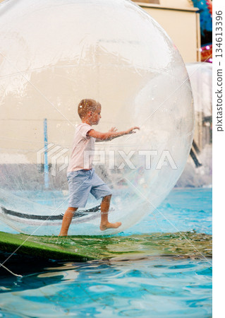 Child Enjoying Water Walking in Inflatable Zorb Ball at Amusement Park 134613396