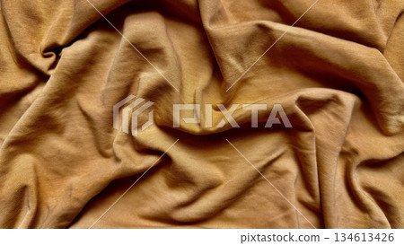 golden brown fabric texture wrinkles softly in closeup folds evoking warm luxurious depth for wallpaper or banner background 134613426