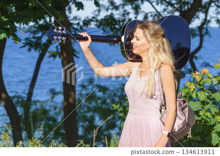 Woman playing acoustic guitar in park 134613911