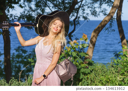 Woman playing acoustic guitar in park Woman playing acoustic guitar in park 134613912