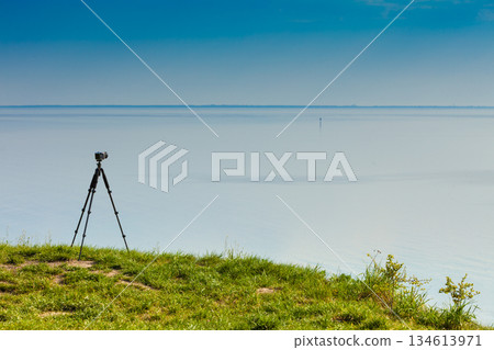 Camera with tripod on coastal cliff 134613971