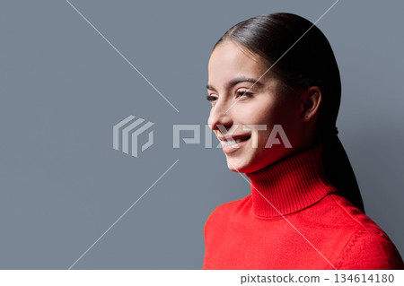 Profile portrait of young smiling woman on gray background Profile portrait of young smiling woman on gray background 134614180