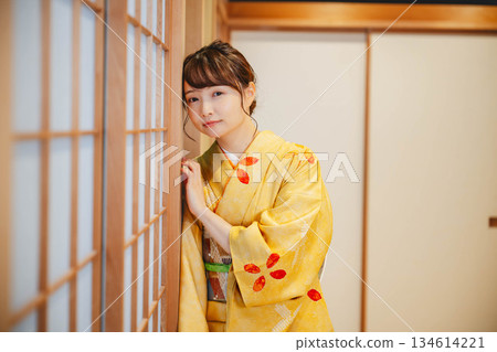 一位身穿和服的年輕女子站在日式房間的障子門旁。 一位身穿和服的年輕女子站在日式房間的障子門旁。 134614221
