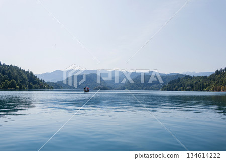 Beautiful Lake Bled in Slovenia with tranquil water, lush green hills, and mountains in the background under a bright clear sky. Old church on the island Beautiful Lake Bled in Slovenia with tranquil water, lush green hills, and mountains in the background under a bright clear sky. Old church on the island 134614222