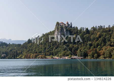Amazing landscape in Slovenia at Lake Blend. Hills with dense forest with a rock with a castle at the lake. Travel and rest Amazing landscape in Slovenia at Lake Blend. Hills with dense forest with a rock with a castle at the lake. Travel and rest 134614226