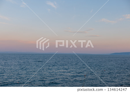 Evening by the sea. Blue ocean surface with calm waves fading into the horizon. Natural seascape symbolizing freedom, calmness, and serenity. Beautiful sea view with mountains after sunset. Holidays Evening by the sea. Blue ocean surface with calm waves fading into the horizon. Natural seascape symbolizing freedom, calmness, and serenity. Beautiful sea view with mountains after sunset. Holidays 134614247