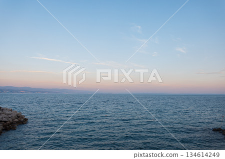 Peaceful ocean horizon with calm waves and pastel sky at dusk. Minimalist seascape for travel, nature, and relaxation themes at sunset. Evening by the sea Peaceful ocean horizon with calm waves and pastel sky at dusk. Minimalist seascape for travel, nature, and relaxation themes at sunset. Evening by the sea 134614249