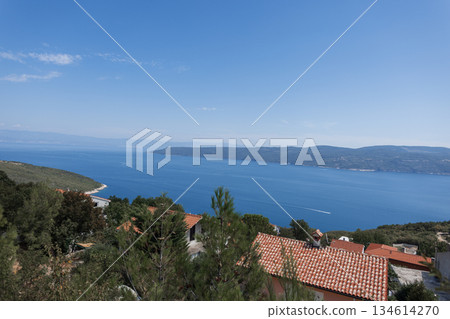 Mediterranean coastal scenery in Croatia with sea, mountains, and village rooftops on a sunny day. Peaceful seascape with gentle waves and wide horizon under a clear sky in Croatia. Mediterranean coastal scenery in Croatia with sea, mountains, and village rooftops on a sunny day. Peaceful seascape with gentle waves and wide horizon under a clear sky in Croatia. 134614270