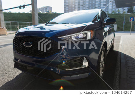 Modern blue SUV parked in the city street, showcasing sleek design, stylish headlights, and urban lifestyle transportation concept with contemporary architecture in the background. Modern blue SUV parked in the city street, showcasing sleek design, stylish headlights, and urban lifestyle transportation concept with contemporary architecture in the background. 134614297