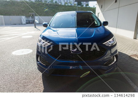 Urban transportation concept with parked automobile, shining headlights, and city background. Blue SUV automobile parked outdoors, stylish rear view shot. Urban transportation concept with parked automobile, shining headlights, and city background. Blue SUV automobile parked outdoors, stylish rear view shot. 134614298