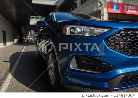 Automobile parked in modern city environment with focus on stylish vehicle details. Blue automobile side profile view parked near concrete industrial wall. Automobile parked in modern city environment with focus on stylish vehicle details. Blue automobile side profile view parked near concrete industrial wall. 134614304