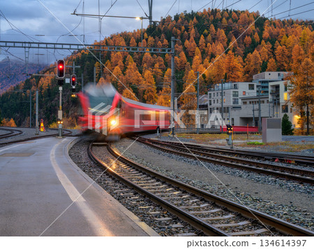 Blurred red passenger train passing mountain railway station 134614397