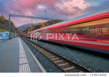Blurred red passenger train passing mountain railway station 134614400