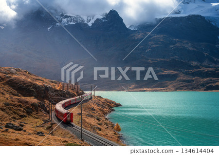Aerial view of red train, curving railroad, turquoise lake 134614404