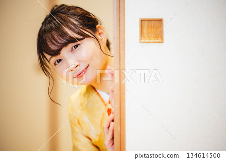 A young woman in a kimono opening a sliding door in a Japanese-style room 134614500