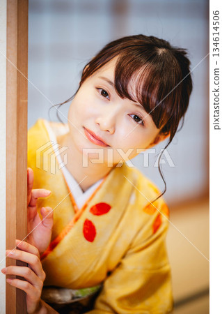A young woman in a kimono opening a sliding door in a Japanese-style room 134614506