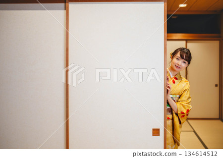 A young woman in a kimono opening a sliding door in a Japanese-style room A young woman in a kimono opening a sliding door in a Japanese-style room 134614512