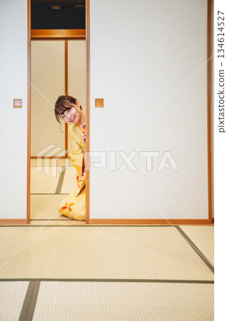 A young woman in a kimono opening a sliding door in a Japanese-style room A young woman in a kimono opening a sliding door in a Japanese-style room 134614527