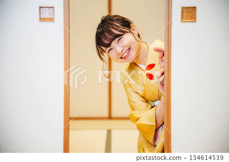 A young woman in a kimono opening a sliding door in a Japanese-style room 134614539