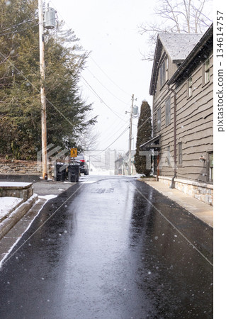 A street is covered in snow and has a few cars parked on it A street is covered in snow and has a few cars parked on it 134614757