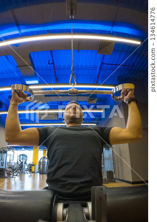 A man is lifting weights in a gym A man is lifting weights in a gym 134614776