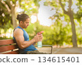 Man athlete taking break hydrating in park 134615401