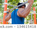 Unrecognizable athlete training calisthenics on pull up bar outdoors 134615418