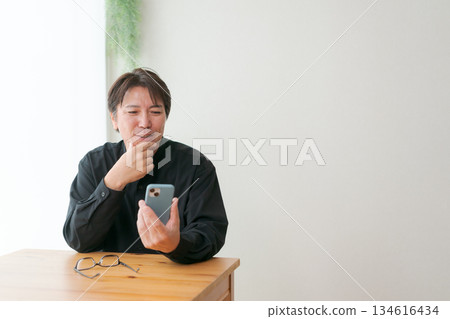 Middle-aged man operating a smartphone 134616434