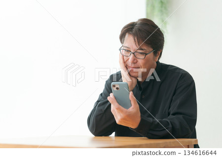 Middle-aged man operating a smartphone Middle-aged man operating a smartphone 134616644
