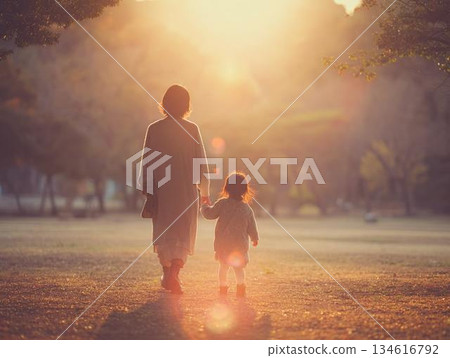 黃昏時分，公園裡，一對父母手牽手散步，從背後拍攝的畫面。 134616792
